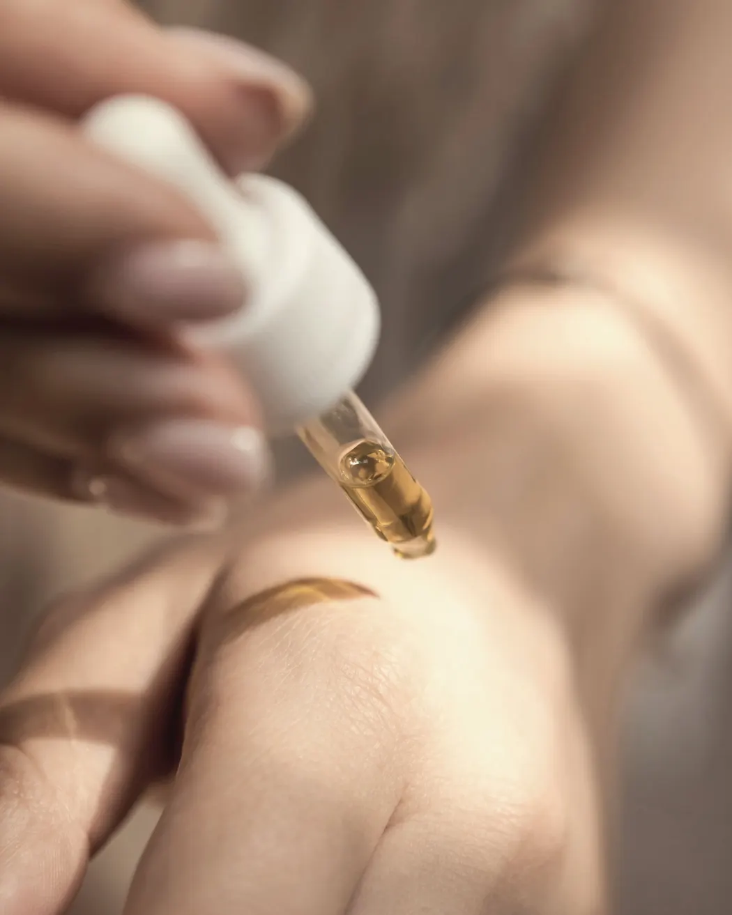 Contagocce di siero dorato sulla pelle